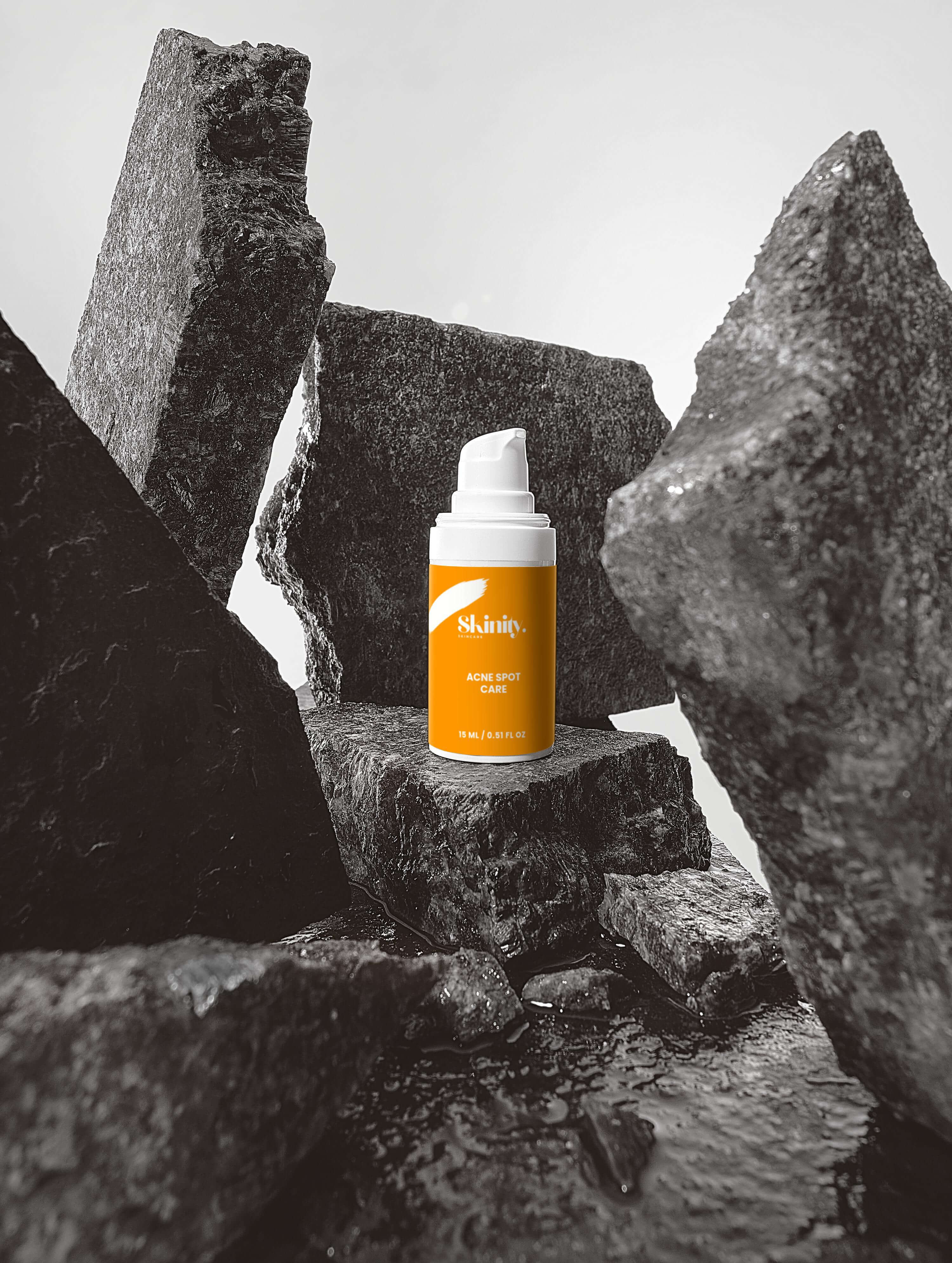 Acne Spot Care Serum for all skin types displayed on textured stone background.