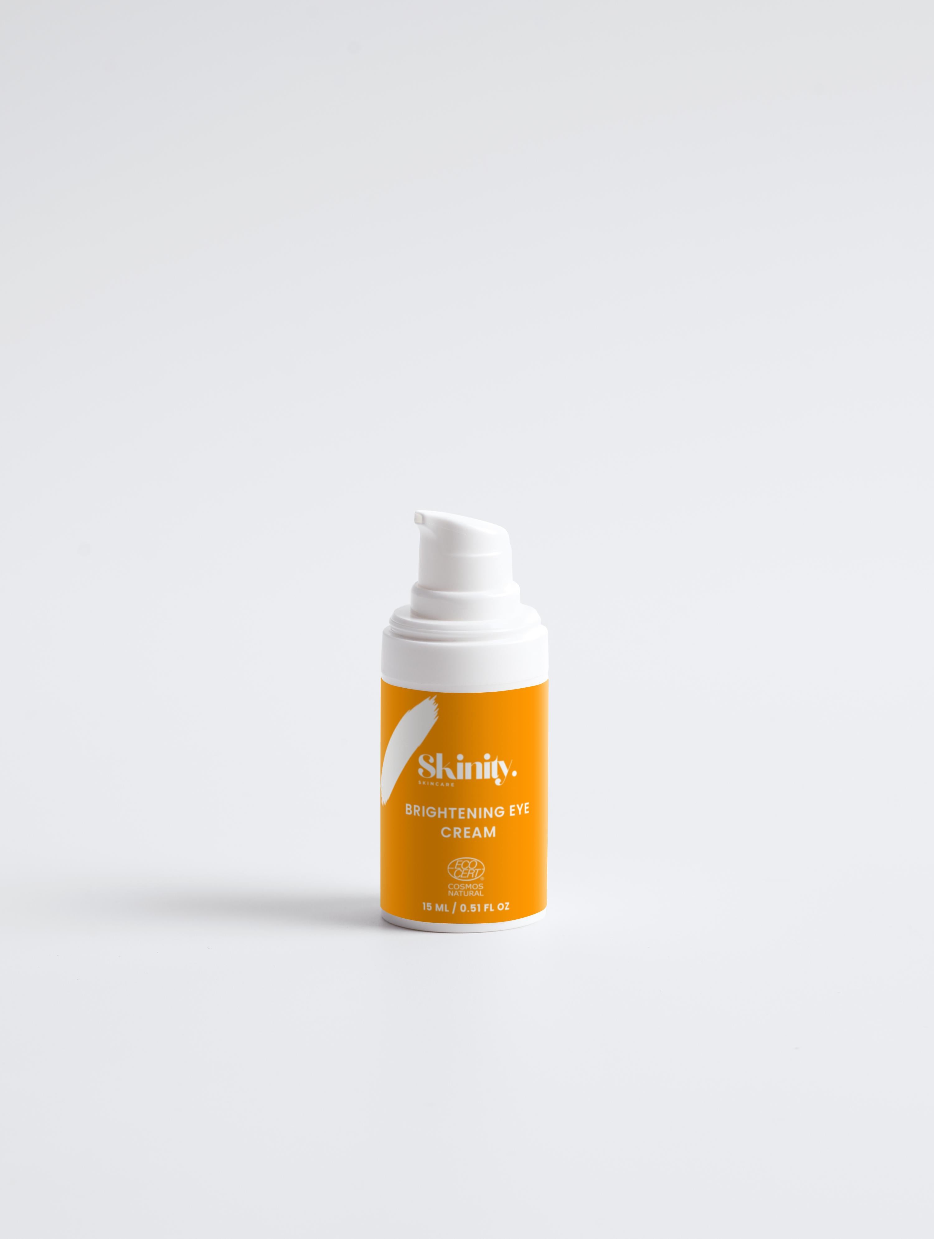 Brightening Eye Cream for All skincare in a pump bottle with a vibrant orange label on a white background.