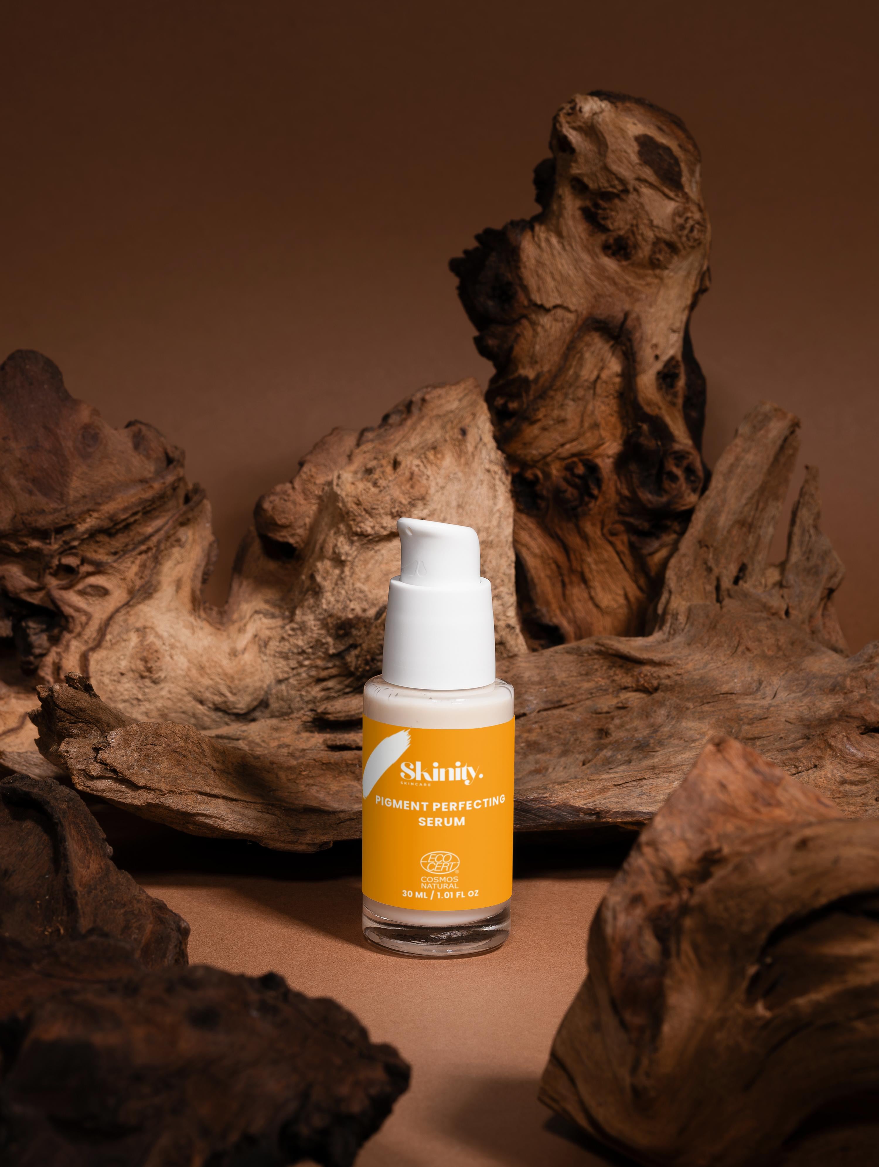 Pigment Perfecting Serum for All Skin surrounded by natural wood texture, showcasing its eco-friendly packaging.