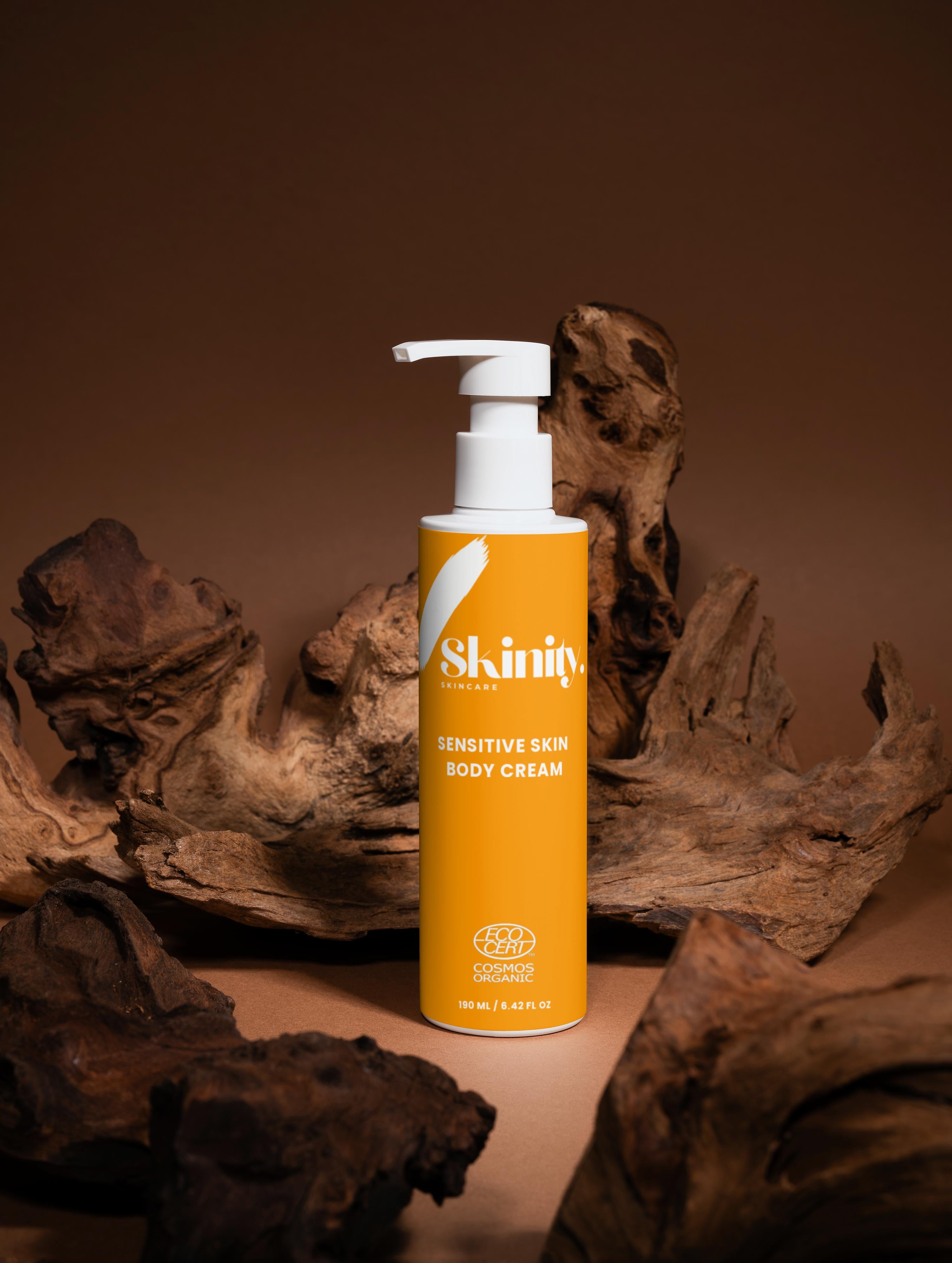 Sensitive Skin Body Cream Vegan in a stylish bottle with pump dispenser on a wooden background.