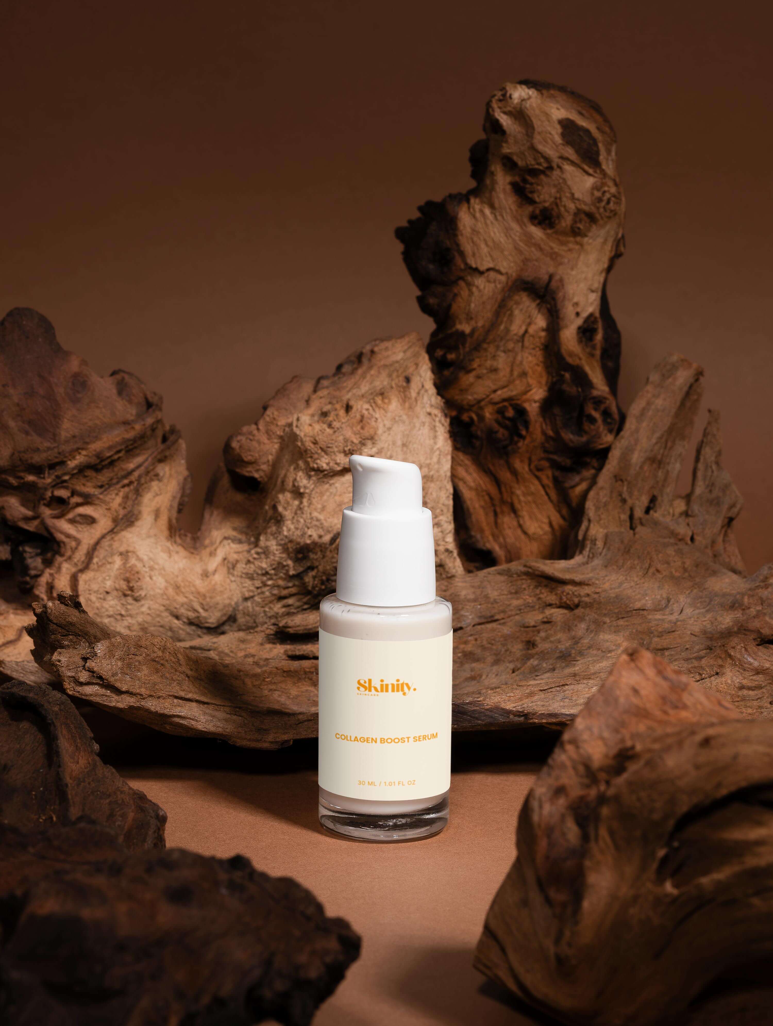 Collagen boost serum for all skin in a clear bottle surrounded by natural wood textures.