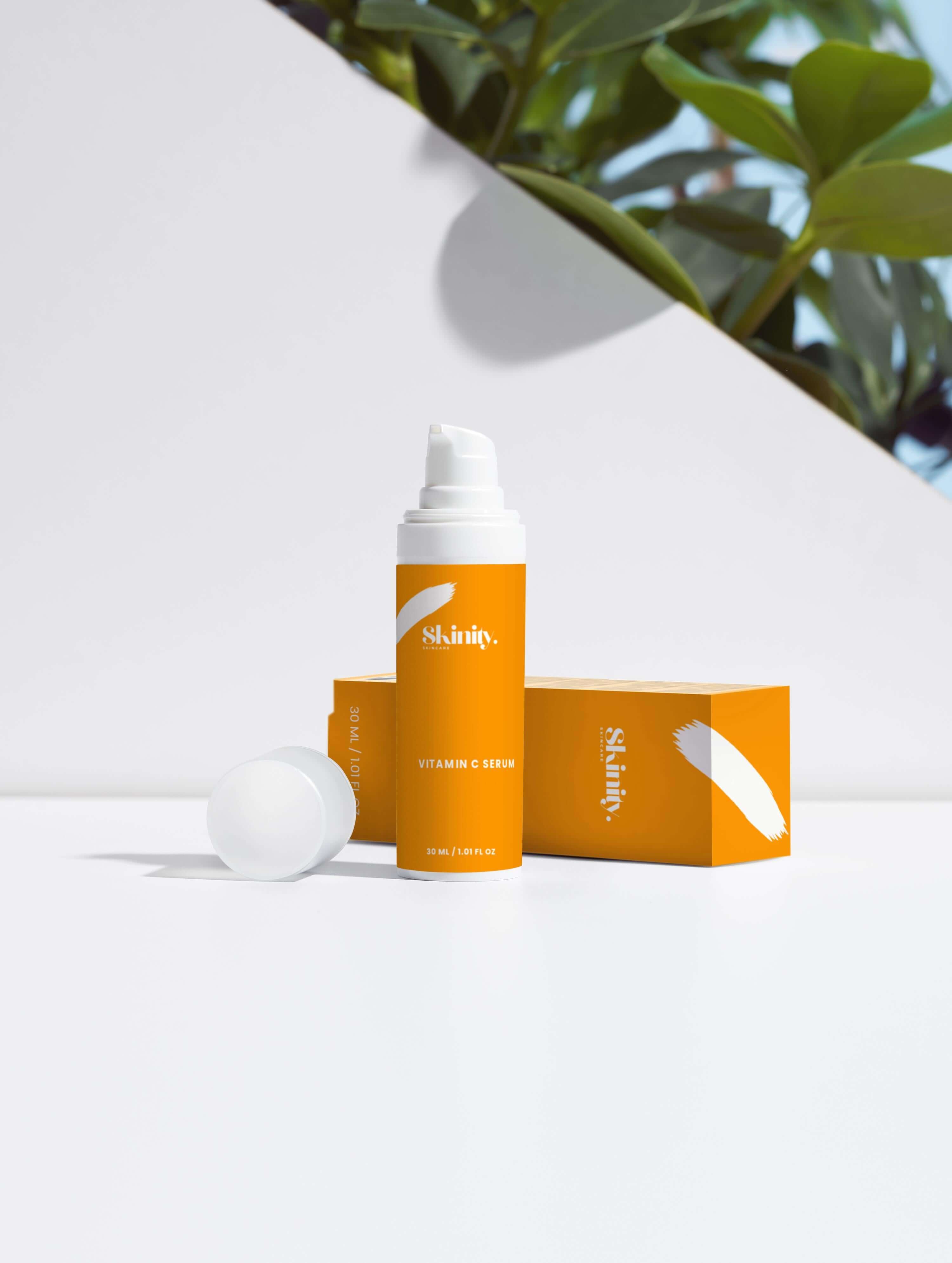 Vitamin C Serum for all skincare displayed in a bright packaging on a white surface with greenery in the background.