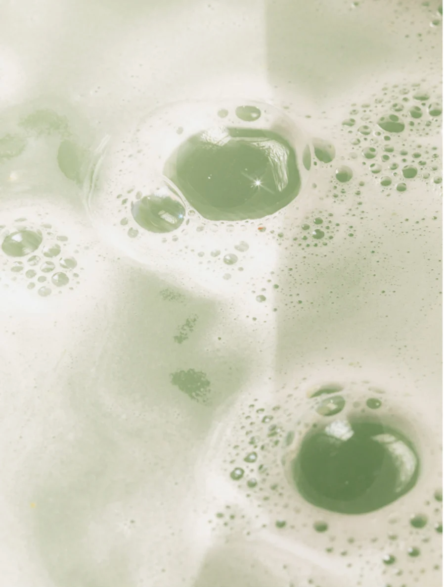 Gloss Shampoo Smoky Green Vetiver bubbles in a green, foamy mixture, showcasing its refreshing and cleansing properties.