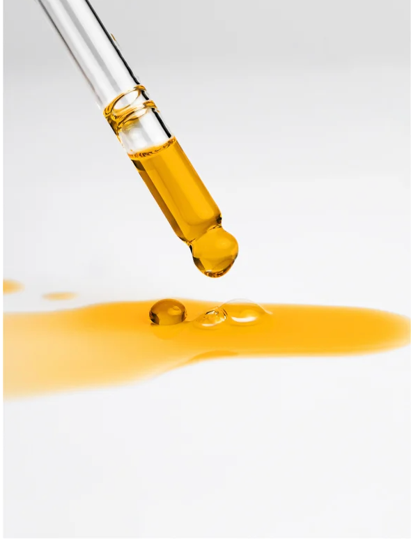 Nourishing Facial Oil For All Skin dripping from a pipette, showcasing its golden hue and nourishing properties.