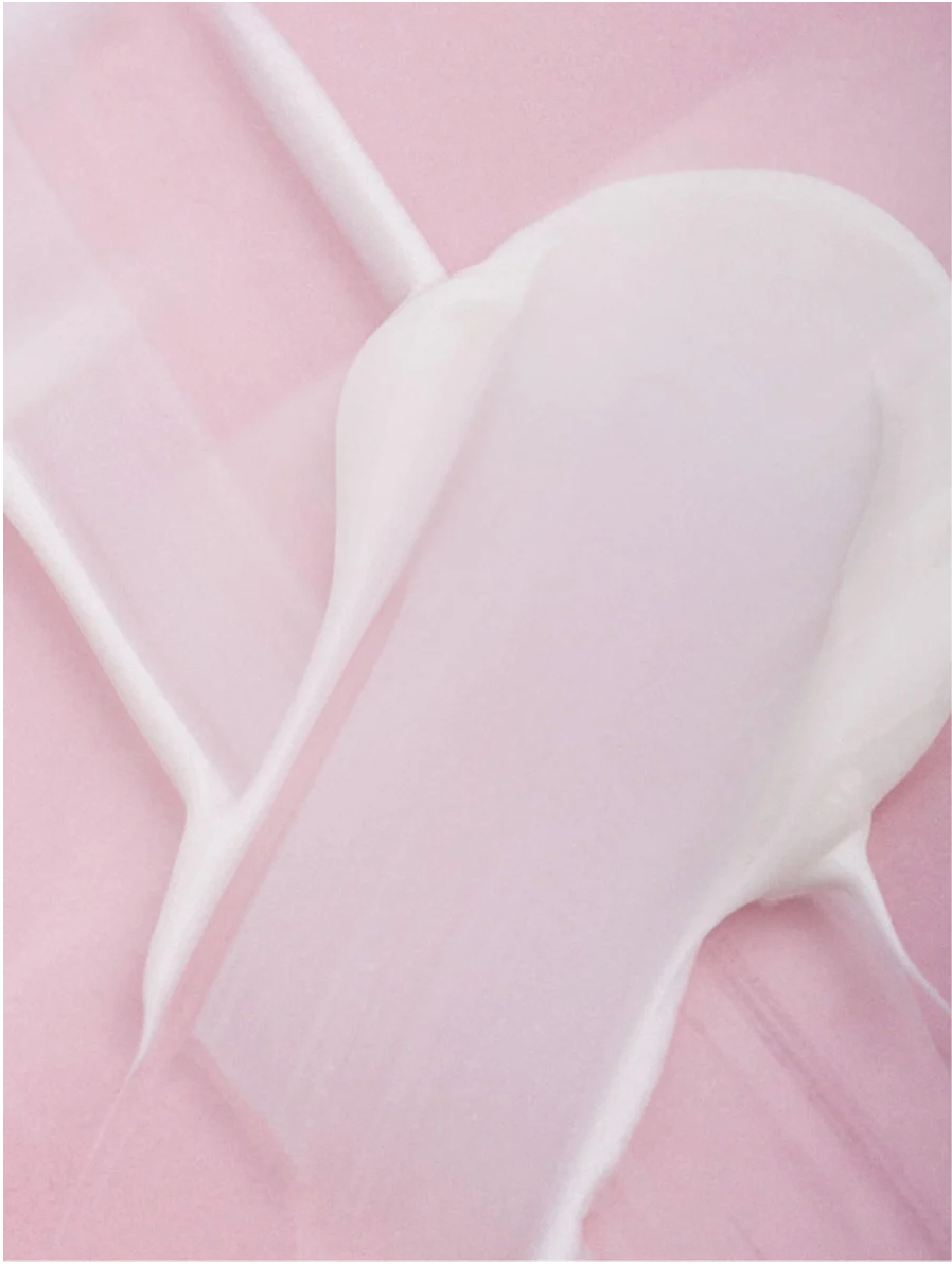 Smoothing eye cream texture spread on a pink surface, showcasing its silky and hydrating properties.