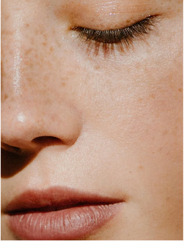 Close-up of a freckled face showcasing clear skin with natural beauty and soft lips.