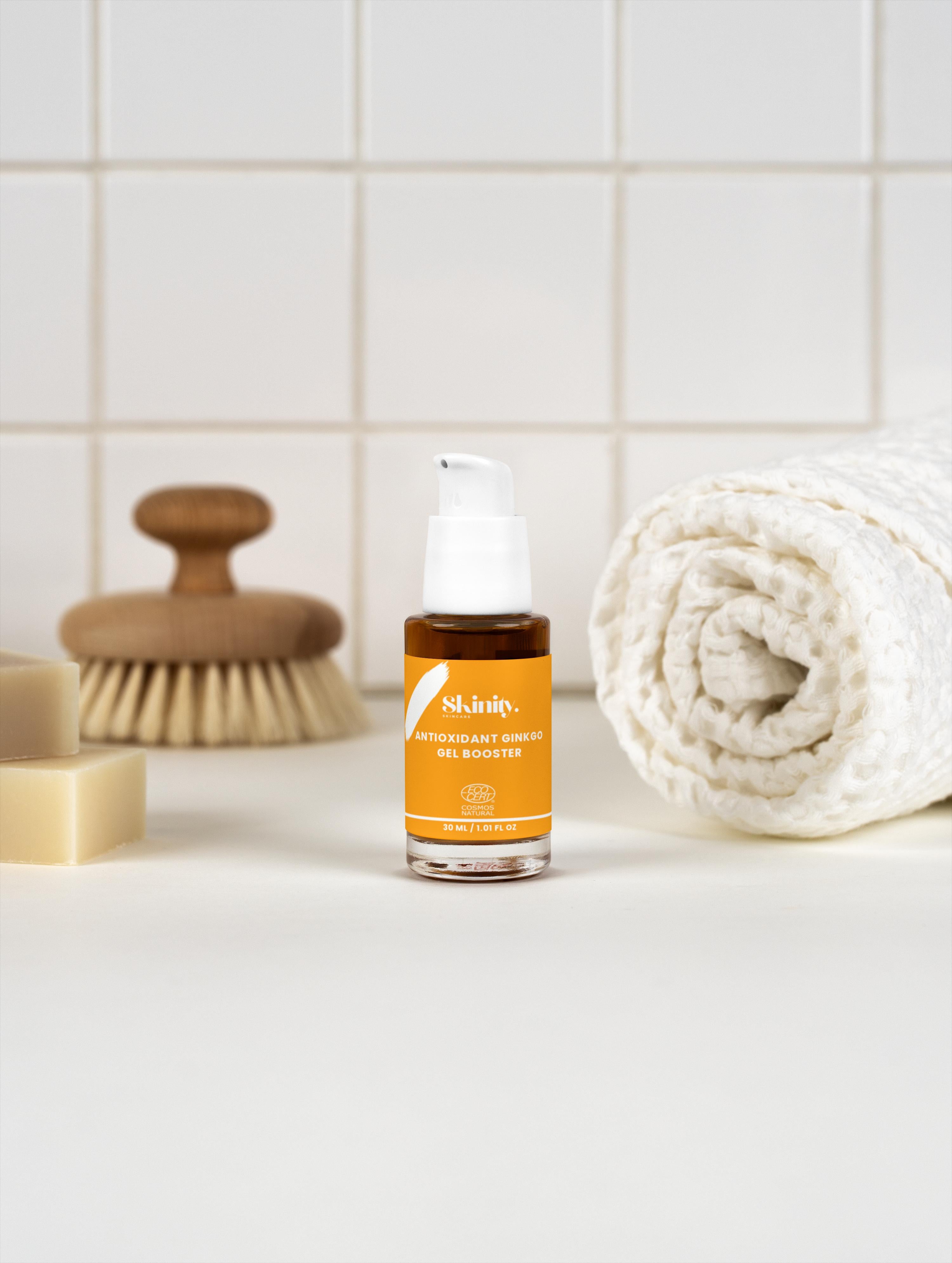 Antioxidant Ginkgo Gel Booster in a stylish bottle on a clean vanity with a towel and cleansing brush.