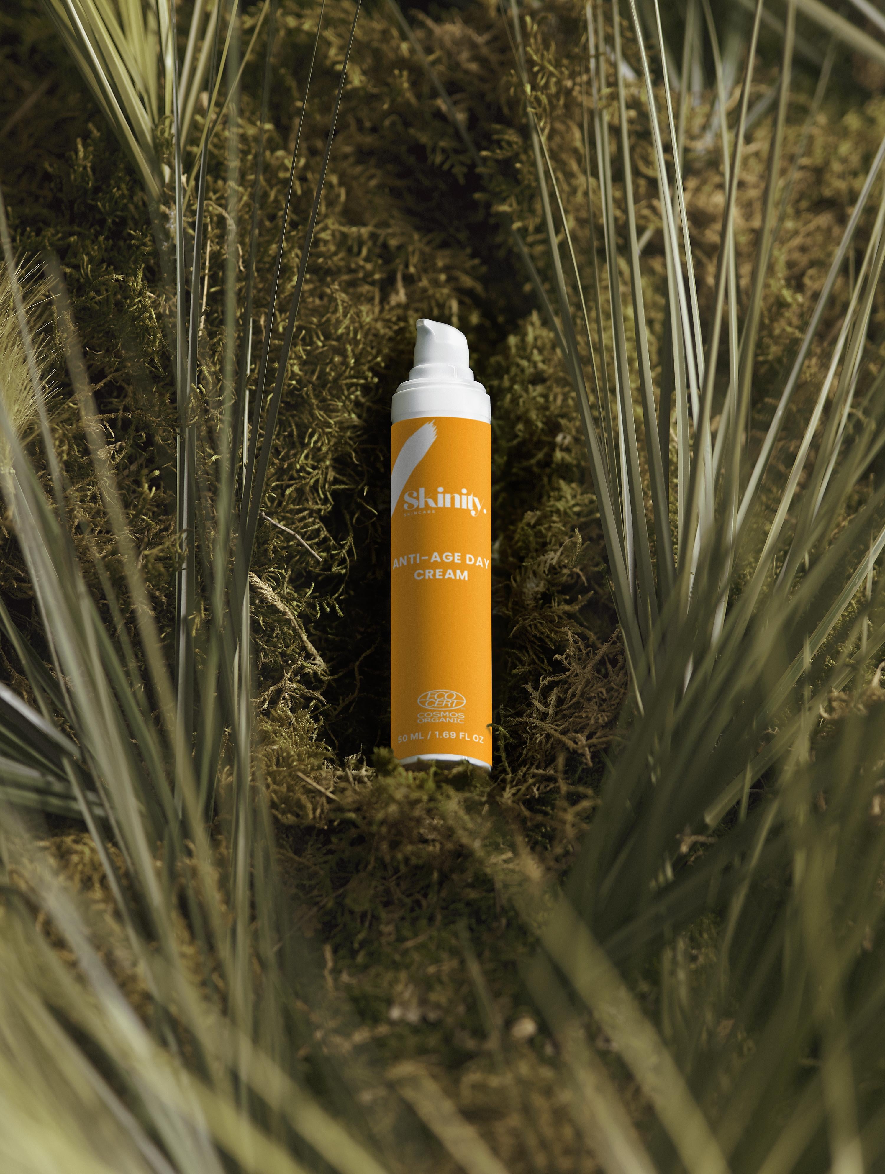 Anti-Age Day Cream For All Skin on a bed of moss and palm leaves, showcasing its eco-friendly packaging.