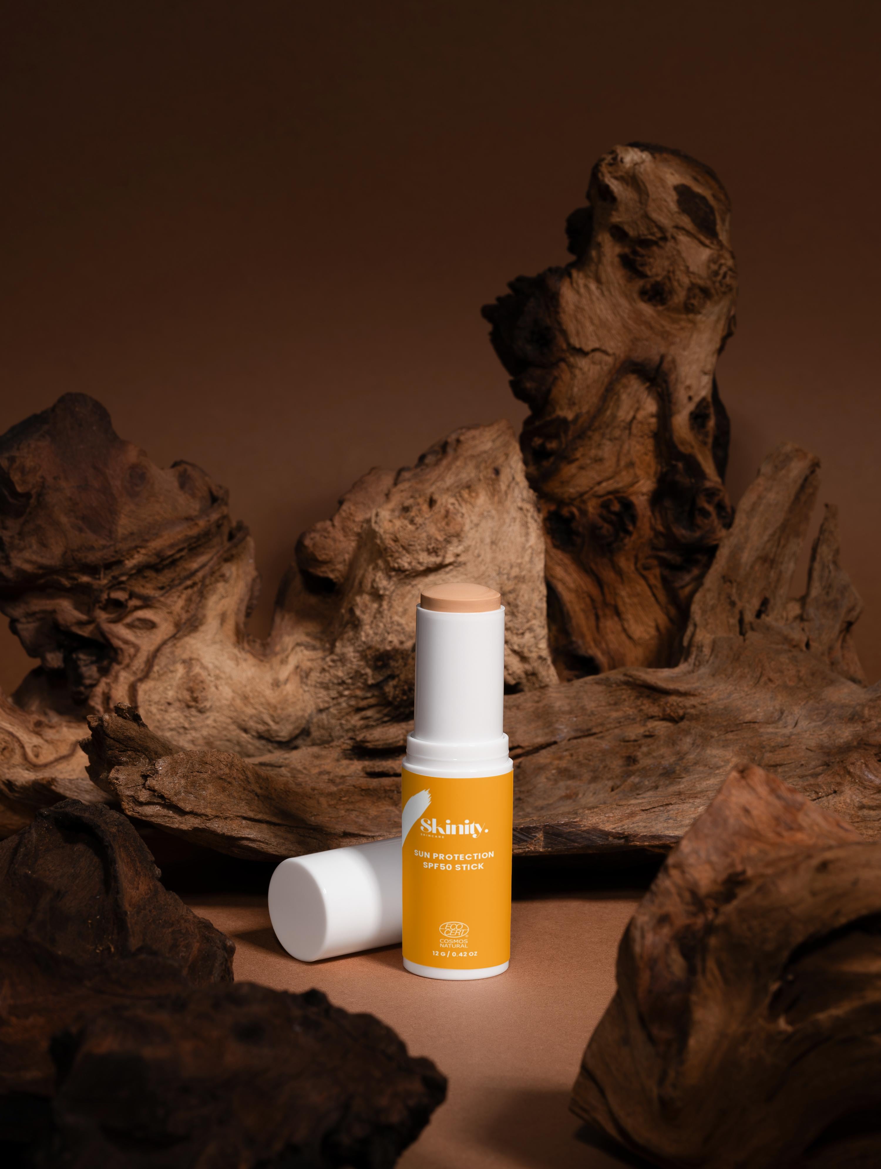 SPF 50 tinted sunscreen stick displayed on textured wood background, showcasing eco-friendly and certified quality.