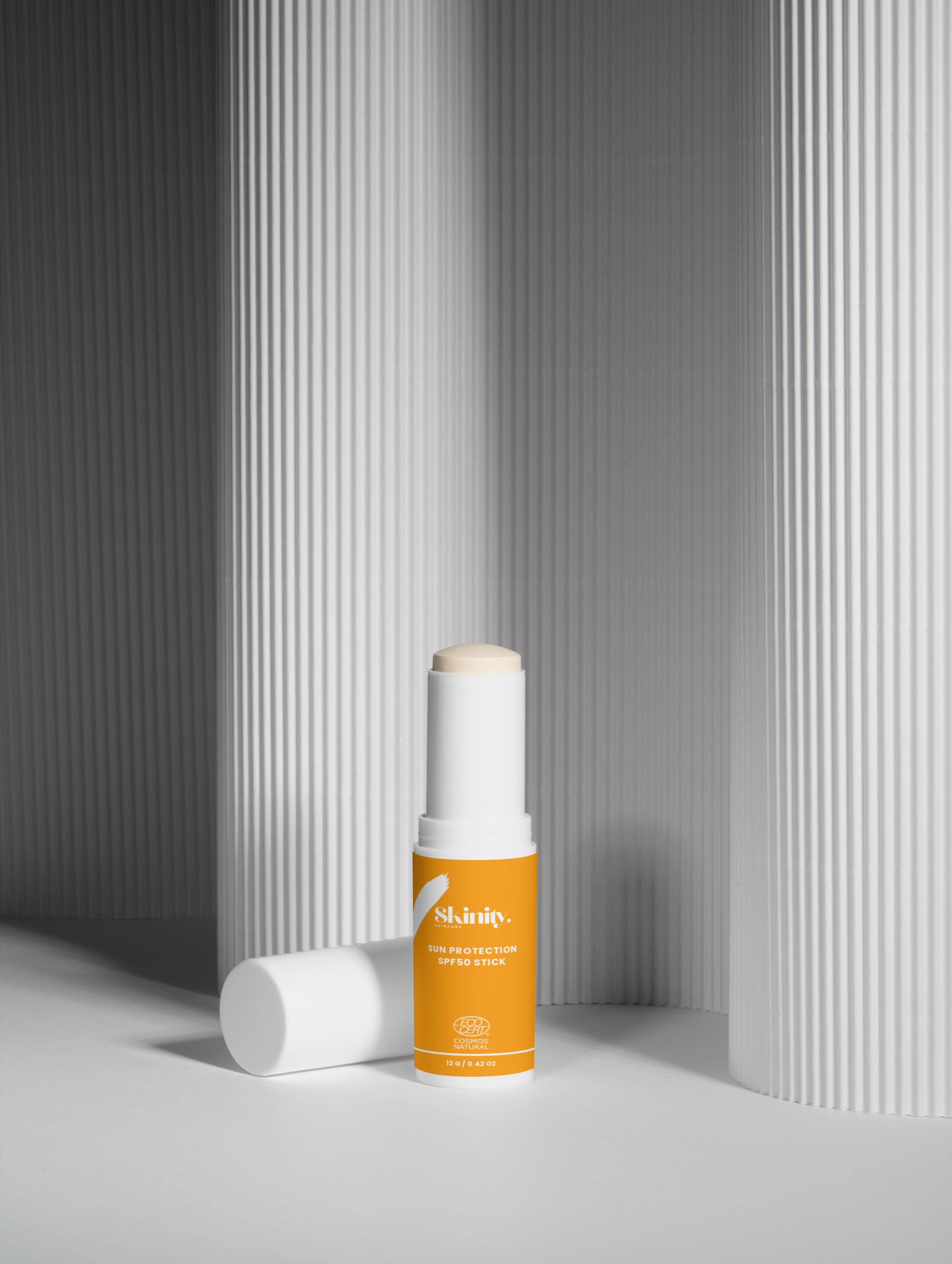 Sun Protection SPF50 Stick no tint displayed next to sleek white and orange packaging in a modern setting.