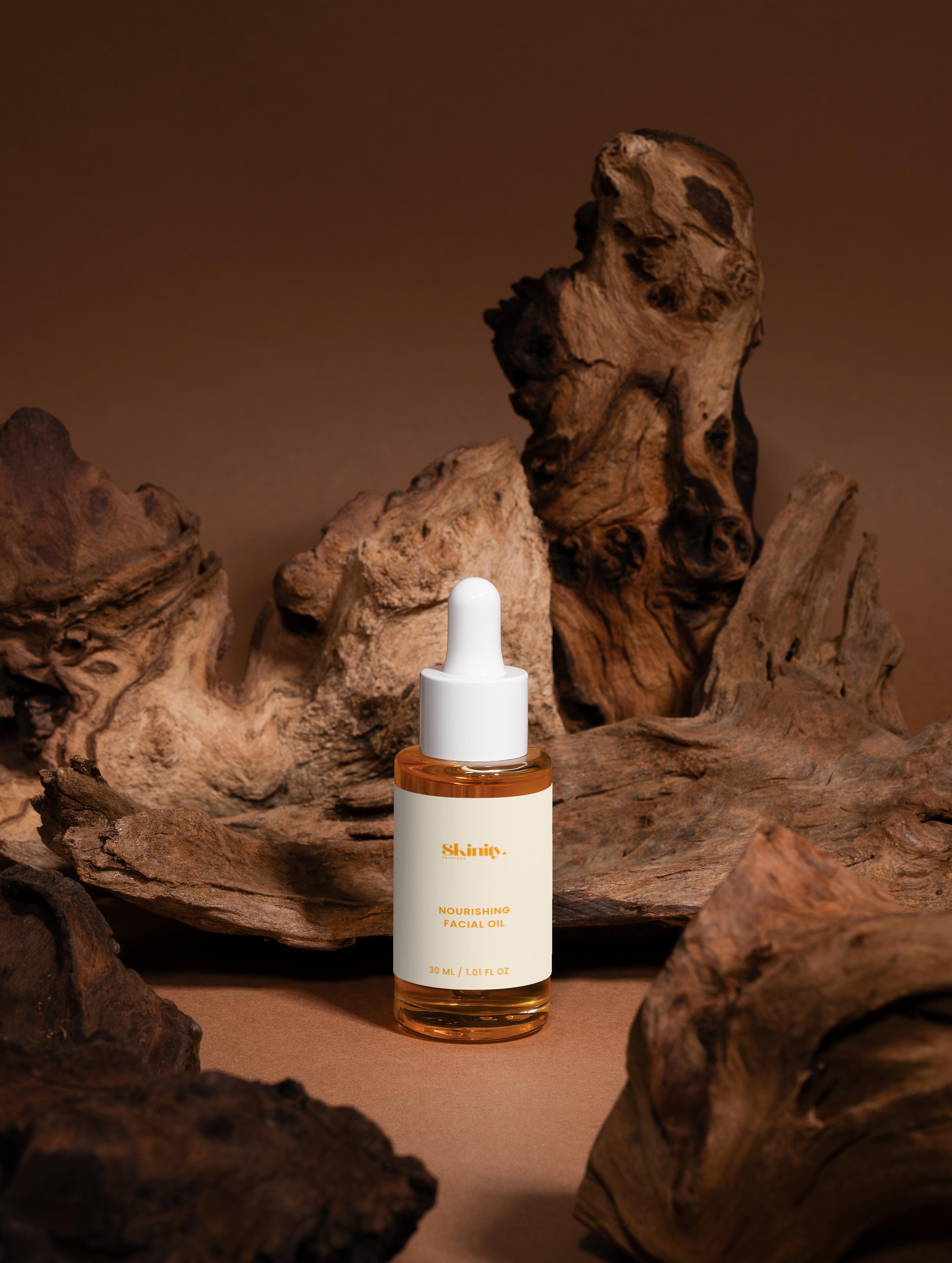 Nourishing facial oil for all skin displayed in a glass dropper bottle surrounded by natural wood elements.